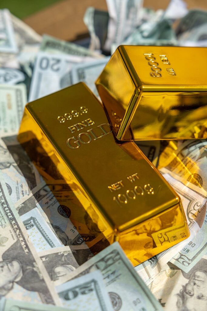 Two gold bars resting on a pile of US dollar bills, representing a portfolio shift towards real assets during a monetary reset.